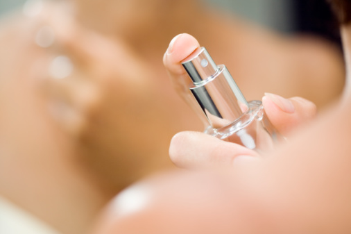 Woman spraying perfume on neck, close up